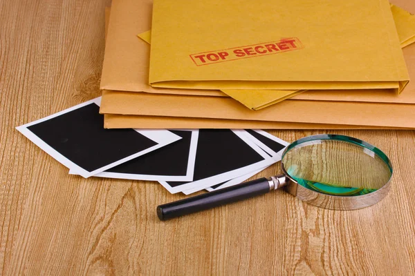 Φάκελοι με κορυφαίο μυστικό σφραγίδα με φωτογραφικά χαρτιά και μεγεθυντικό φακό σε w — Φωτογραφία Αρχείου