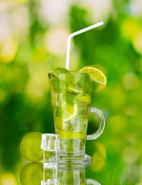 Стакан коктейля с лаймом и мятой на зеленом фоне — стоковое фото