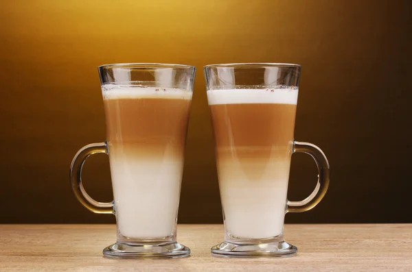 Latte parfumé dans des tasses en verre sur une table en bois sur fond brun — Photo