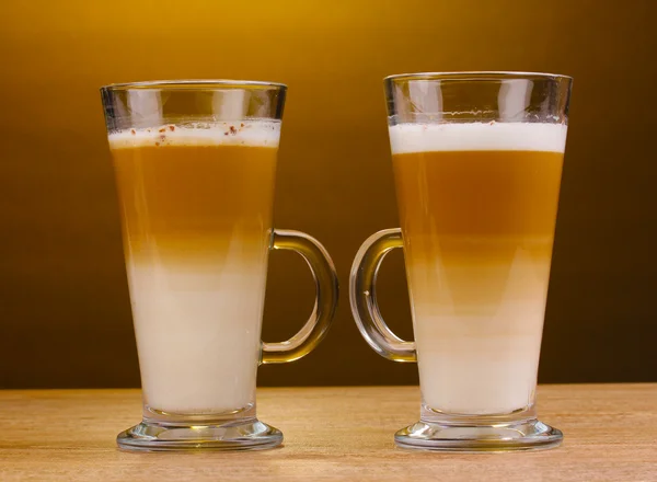 Latte perfumado com latte em copos de vidro na mesa de madeira no fundo marrom — Fotografia de Stock