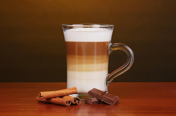 Latte au cappuccino parfumé dans une tasse en verre à la cannelle et au chocolat sur boisé — Photo
