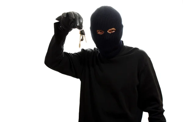 Räuber in schwarzer Maske mit Schlüsseln auf weißem Hintergrund — Stockfoto