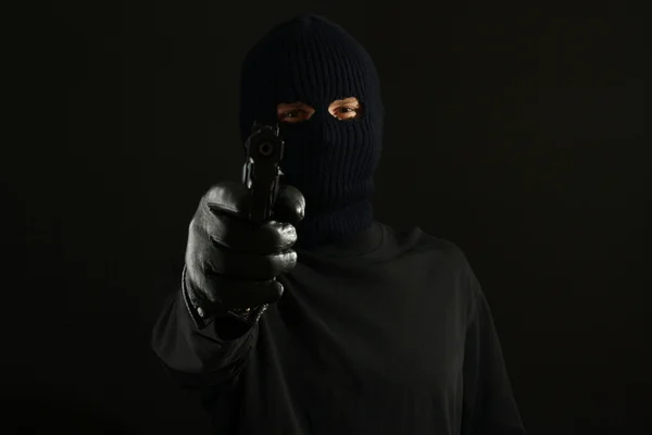Räuber mit schwarzer Maske und Pistole isoliert auf schwarz — Stockfoto
