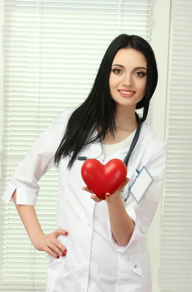 Jeune beau médecin avec stéthoscope tenant coeur — Photo