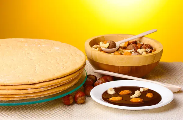 Tortas para pastel sobre soporte de vidrio y nueces sobre mesa sobre fondo amarillo —  Fotos de Stock