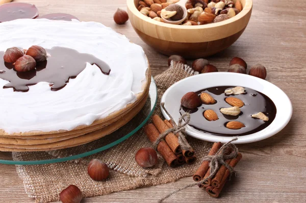 Торт на стеклянном стенде и орехи на деревянном столе — стоковое фото