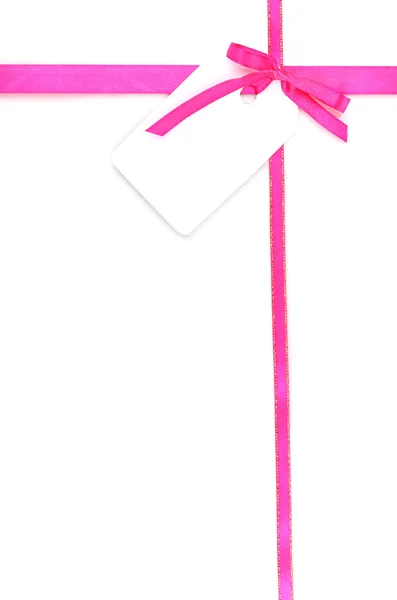 Рожевий атласний лук і стрічка з порожньою подарунковою міткою ізольовані на білому — стокове фото