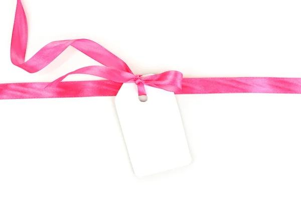 Etiqueta regalo en blanco con lazo de satén rosa y cinta aislada en blanco —  Fotos de Stock