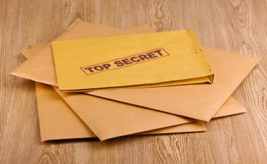 Envelopes with top secret stamp on wooden background clipart