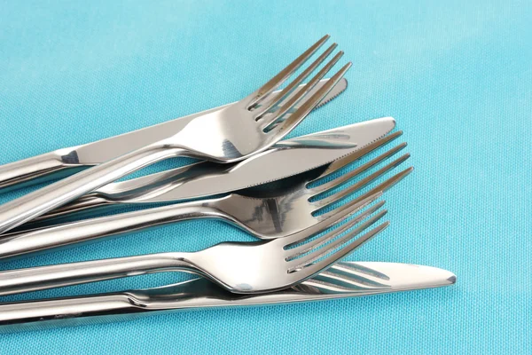 Forks and knives on a blue tablecloth — Stock Photo, Image
