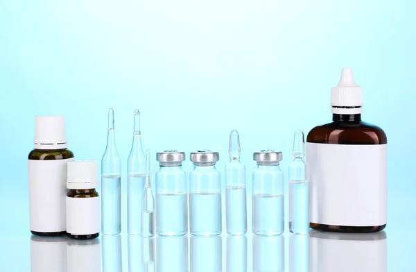 Medizinische Flaschen und Ampullen auf blauem Hintergrund — Stockfoto