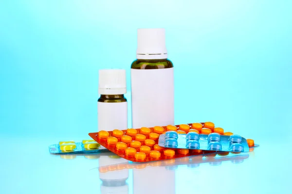 Medical bottles and tablets on blue background — Stock Photo, Image