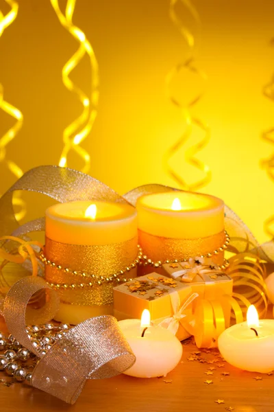 Hermosas velas, regalos y decoración sobre mesa de madera sobre fondo amarillo — Foto de Stock