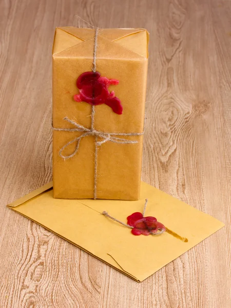 Посылка и конверт с герметичным воском на деревянном фоне — стоковое фото