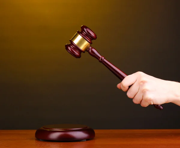 Martelletto del giudice in mano su sfondo marrone — Foto Stock