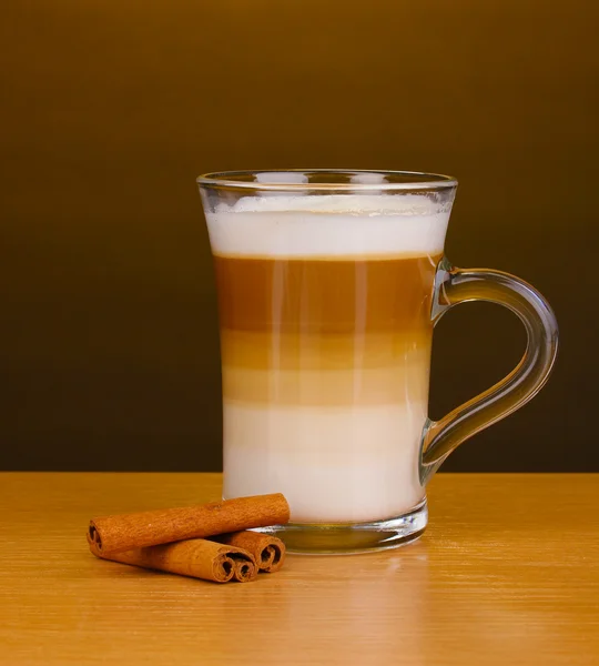 Pachnące? appuccino latte w szklanym pucharze i cynamon na drewnianym stole na czoło — Zdjęcie stockowe