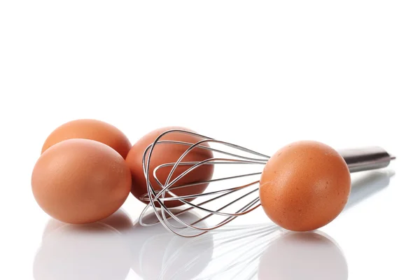 Metalowa Trzepaczka do ubijania jajek i brązowe jaja na białym tle — Zdjęcie stockowe
