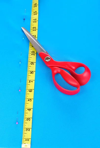 Scissors and measuring tape on blue fabric — Stock Photo, Image