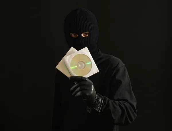 Bandido em máscara preta com discos de CD isolados em preto — Fotografia de Stock