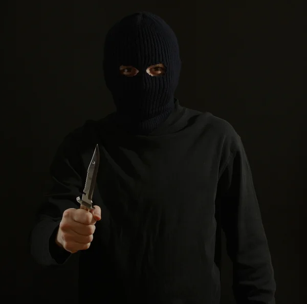 Bandido em máscara preta com faca isolada em preto — Fotografia de Stock