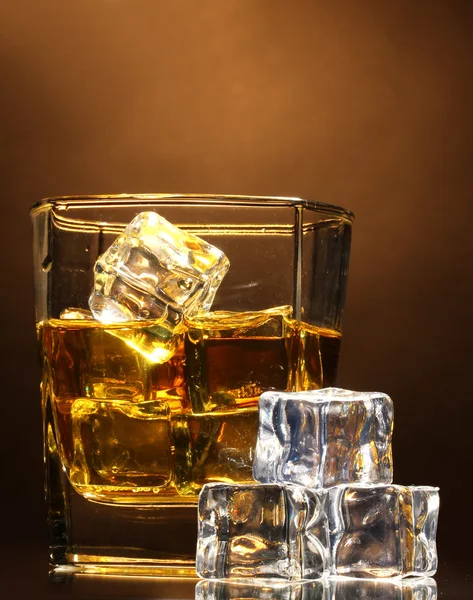 Glass of scotch whiskey and ice on brown background — Stock Photo, Image