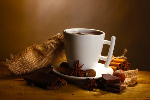 Φλιτζάνι ζεστή σοκολάτα, ξυλάκια κανέλας, καρύδια και σοκολάτα στο ξύλινο τραπέζι o — Φωτογραφία Αρχείου