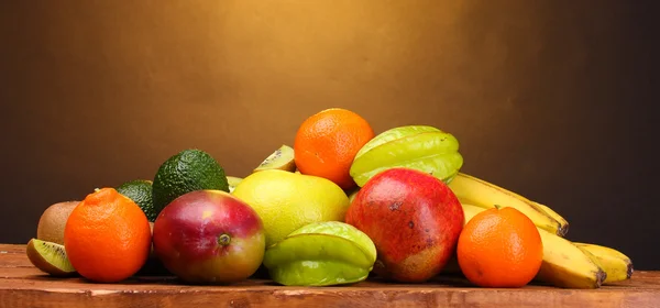 Berbagai macam buah-buahan eksotis di atas meja kayu dengan latar belakang coklat — Stok Foto