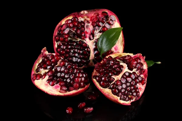 Mogen granatäpple frukt med lämnar på svart bakgrund — Stockfoto