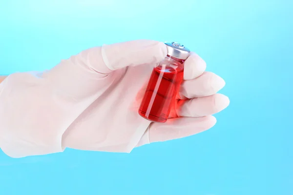 Medicinsk ampull i handen på blå bakgrund — Stockfoto