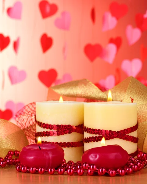 Belles bougies avec décor romantique sur une table en bois sur fond rouge — Photo