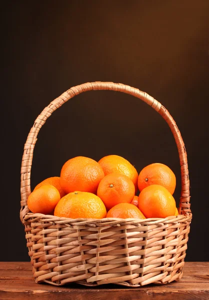 Mandarini in un bel cesto su tavolo di legno su sfondo marrone — Foto Stock