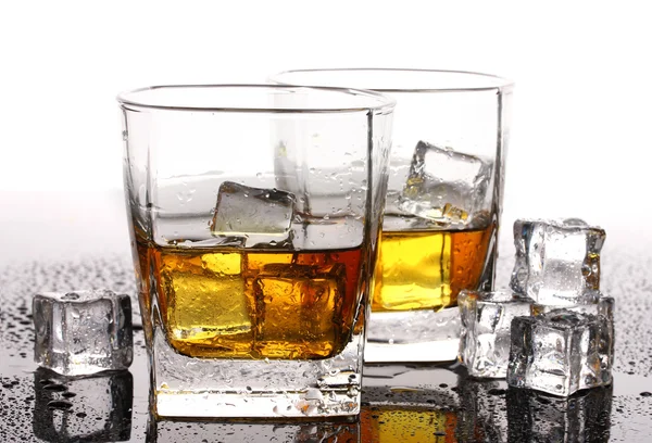 Dwie szklanki whisky szkockiej i lodu na stole na białym tle — Zdjęcie stockowe