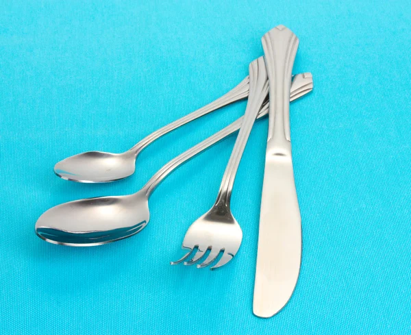 Forchetta, cucchiaio e coltello su una tovaglia blu — Foto Stock