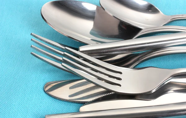 Forks, spoons and knives on a blue tablecloth closeup — Stock Photo, Image