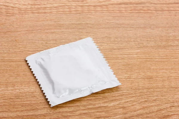 Een condoom op houten achtergrond — Stockfoto