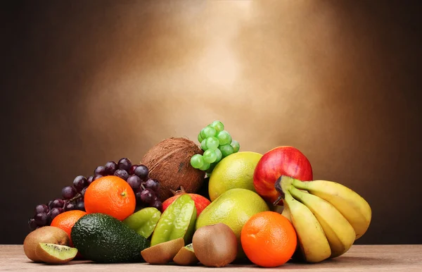 Surtido de frutas exóticas sobre mesa de madera sobre fondo marrón —  Fotos de Stock