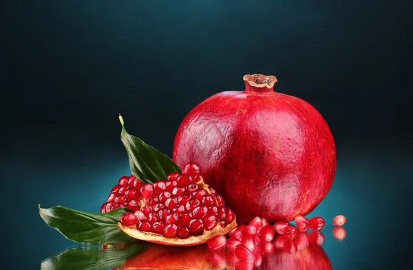 Ripe pomegranate fruit with leaves on blue background — Stock Photo, Image