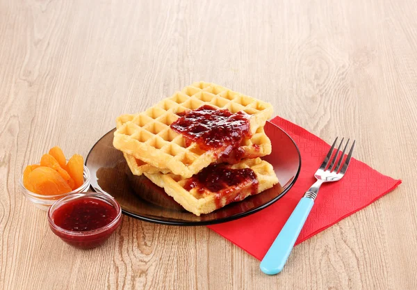 Tasty waffles with jam on plate on wooden background — Stock Photo, Image