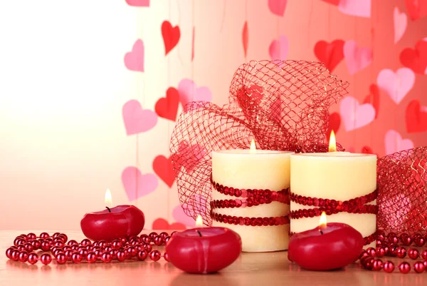 ロマンチックな装飾が施された木製のテーブル、赤の背景に美しいキャンドル — ストック写真