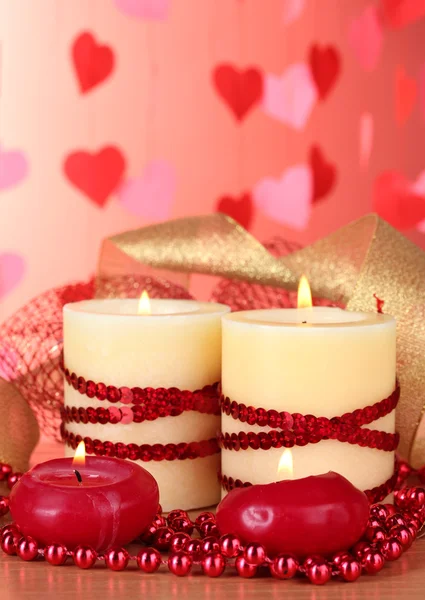Krásný svícen s romantickou výzdobou na dřevěný stůl na červeném pozadí — Stock fotografie