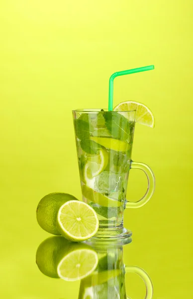Glass of cocktail with lime and mint on green background — Stock Photo, Image