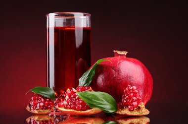 Ripe pomergranate and glass of juice on red background clipart