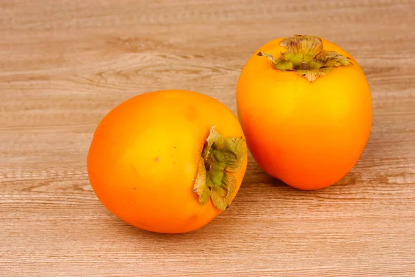 Two appetizing persimmons on wooden background — Stock Photo, Image
