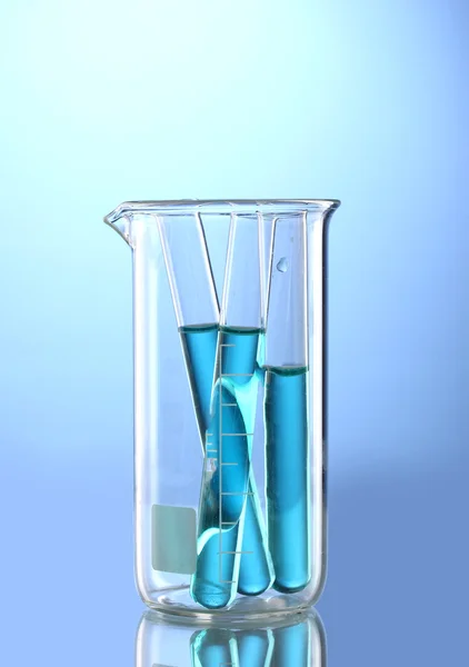 Лабораторные трубки с голубой жидкостью в измерительном стакане с отражением на bl — стоковое фото