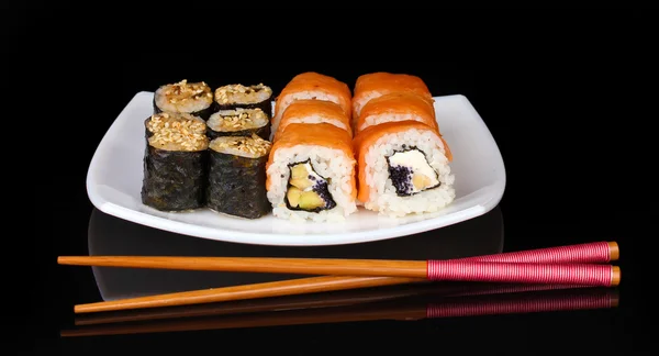 Вкусные рулоны подаются на белой тарелке с палочками для еды, изолированными на черном — стоковое фото