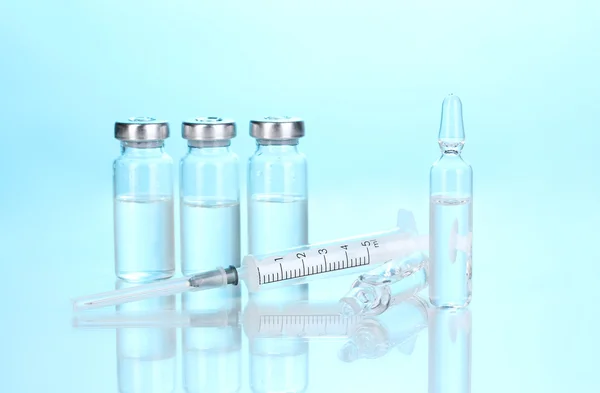 Jeringa y ampollas médicas sobre fondo azul —  Fotos de Stock