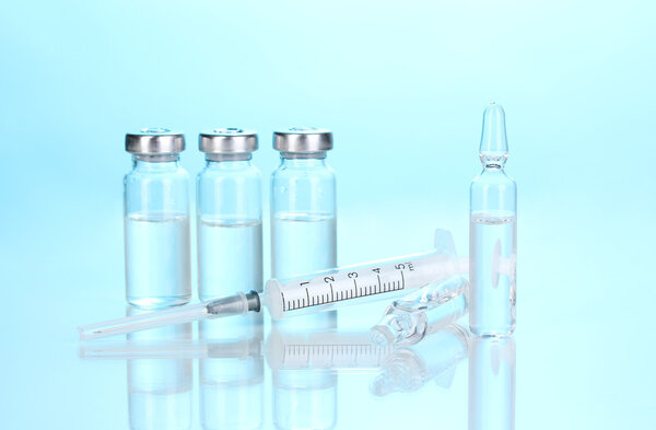 Syringe and medical ampoules on blue background