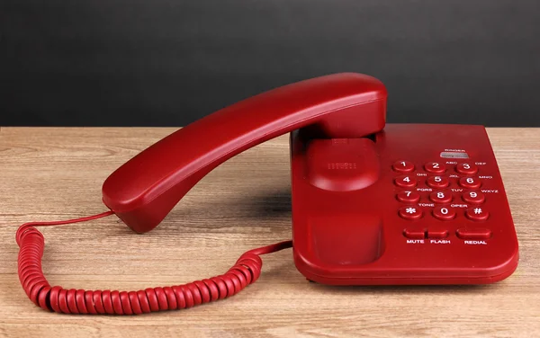 Telefono rosso su tavolo in legno su sfondo grigio — Foto Stock