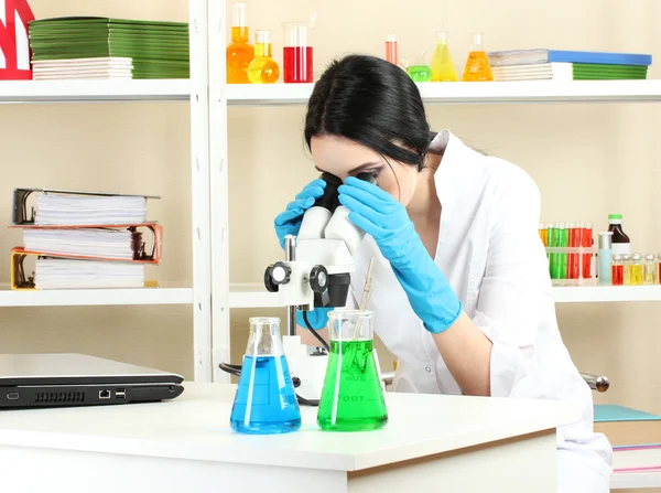 化学実験室の顕微鏡を見て若い女性科学者 — ストック写真