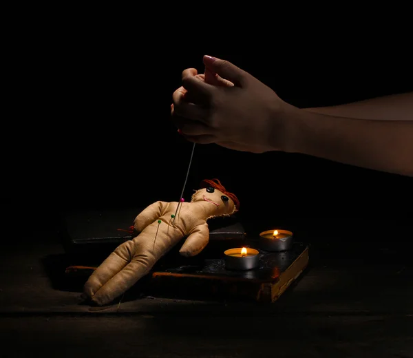 Voodoo-Puppenmädchen durchbohrt von einer Nadel auf einem Holztisch im Kerzenschein — Stockfoto